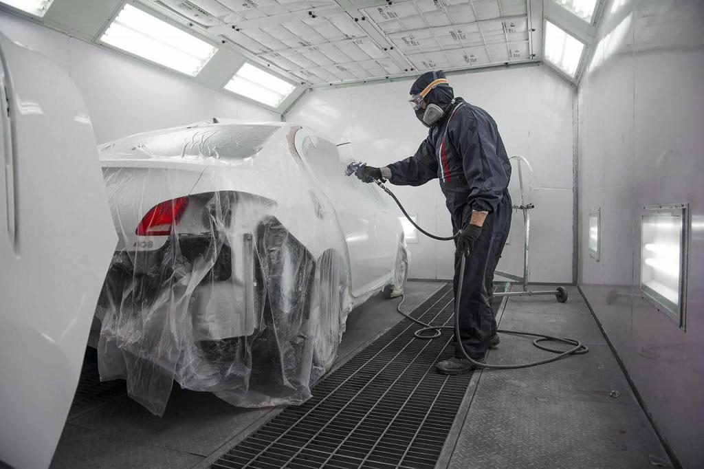 Technician spraying a masked-up car in the booth