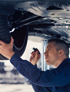 Technician inspecting the underside of a car